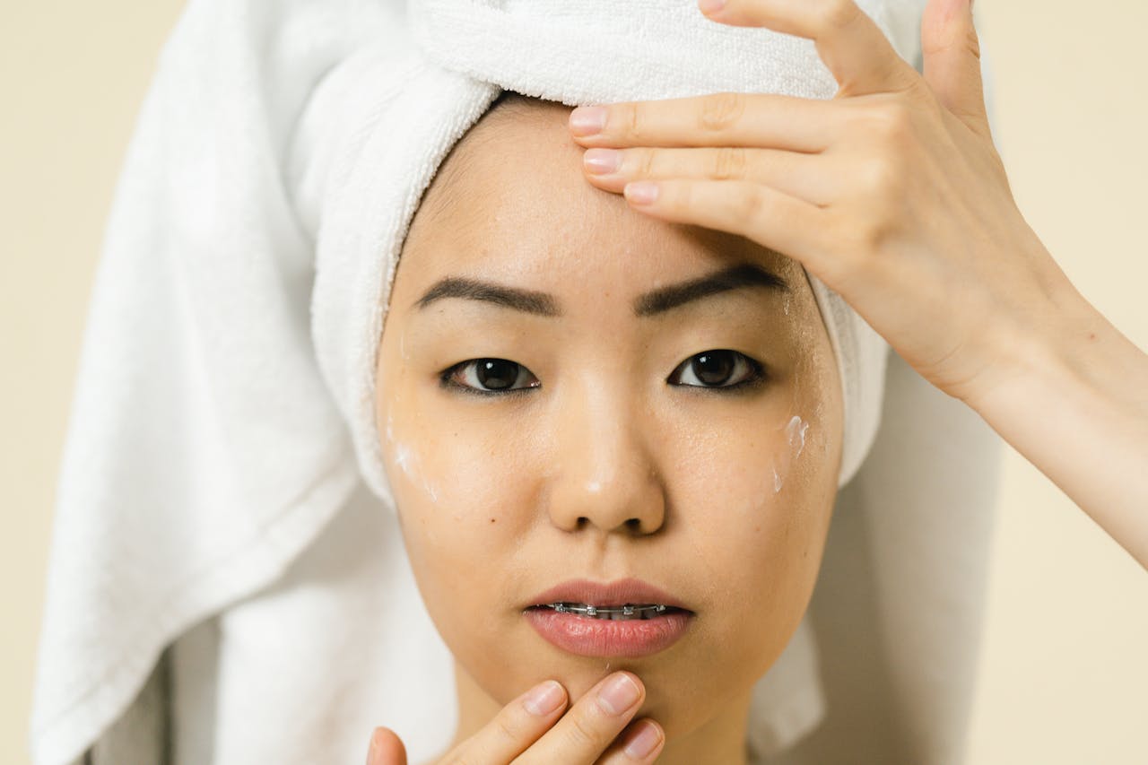 A woman applies facial cream during her daily skincare routine.